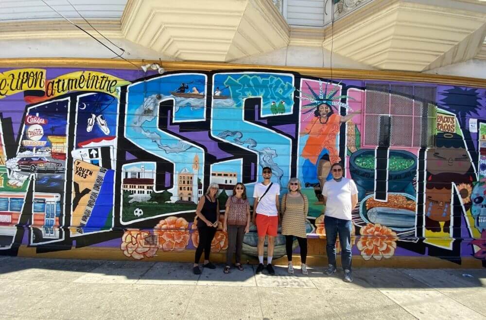 Mission District food tour goers posing by a Mission District mural